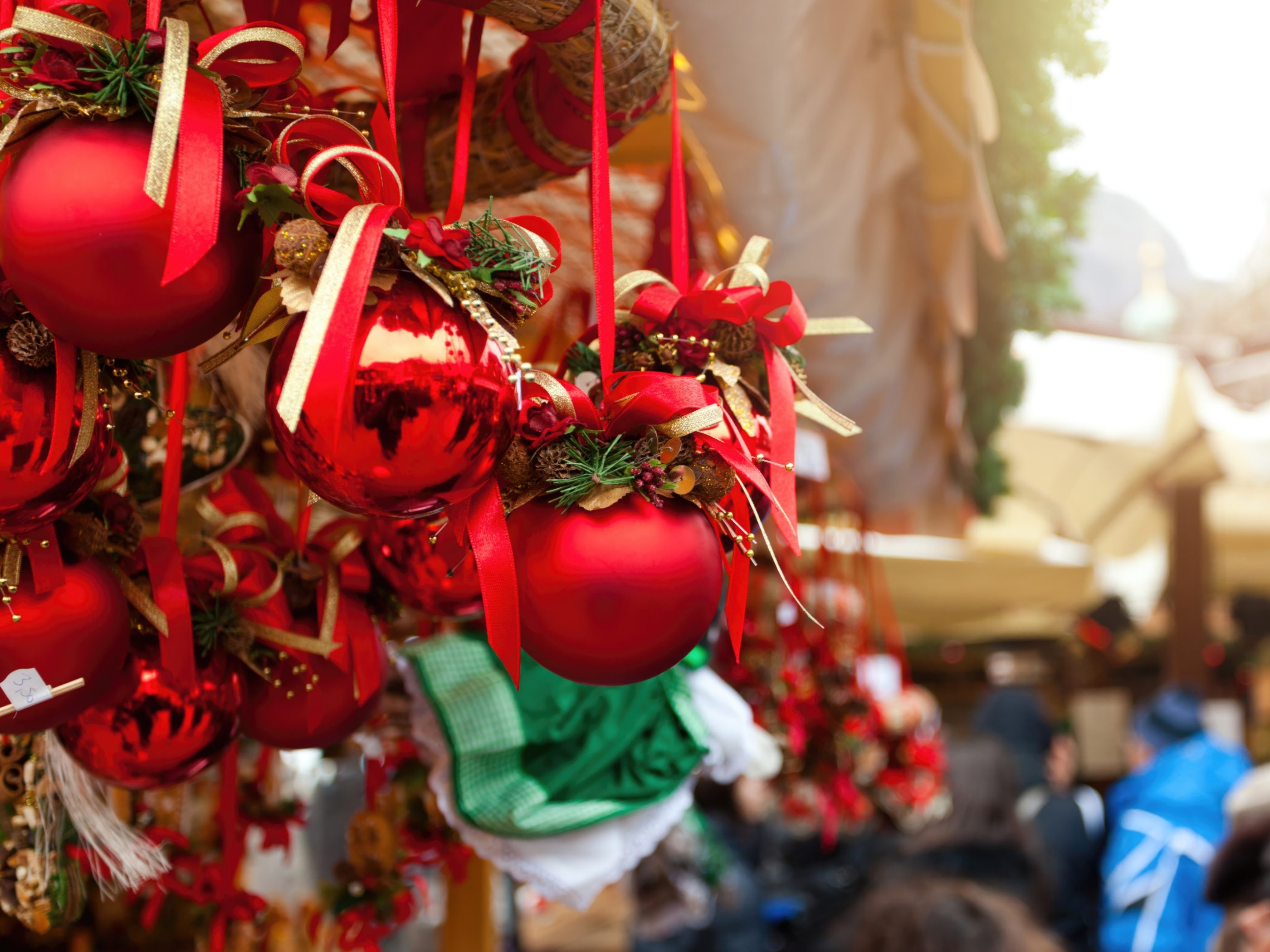 Red christmas balls decorated with ribbons and pine cones hanging at a stall in a christmas market