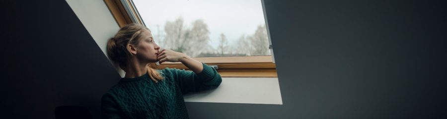 Young woman looking out of attic window