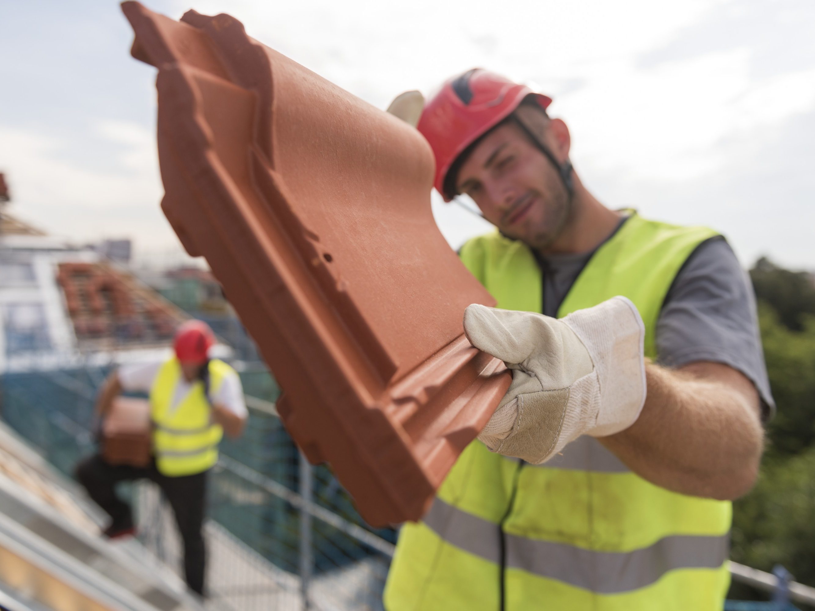 Urban roofers showing product installation roof tiles construction worker wearing hard hat