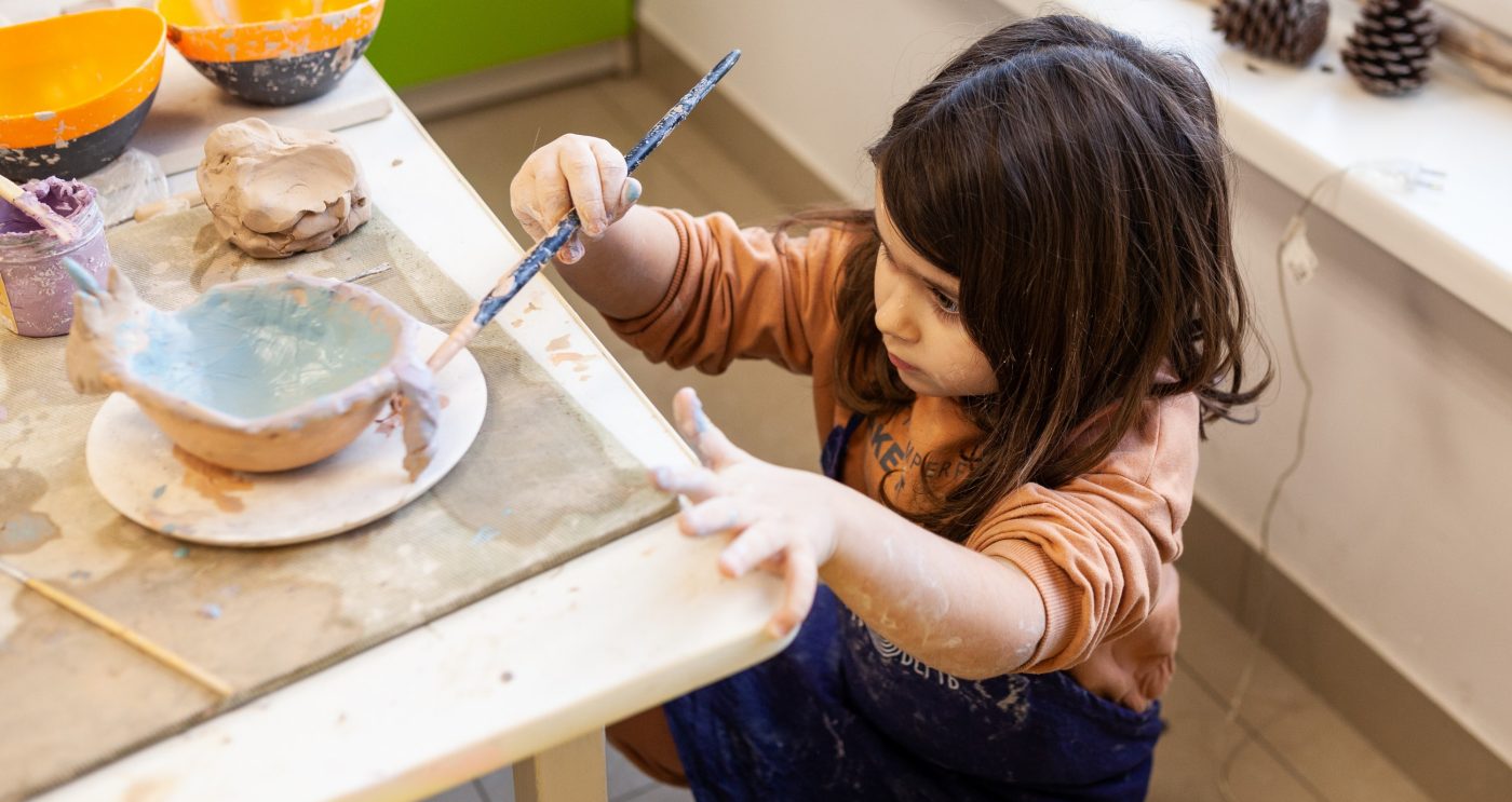 Cute little kid playing with modeling clay in pottery workshop, craft and clay art, child creative activities, education in Arts