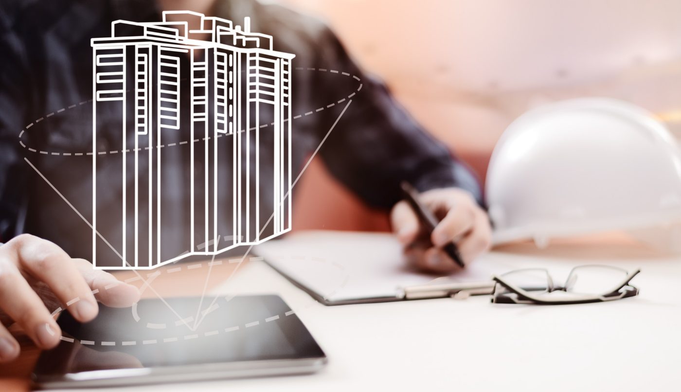 Young blurred architect sitting in the office and designing new building, with digital drawing on tablet PC and paper sketch. Architecture, building and renovation concepts. Great design for advertisement and illustration of architecture business.