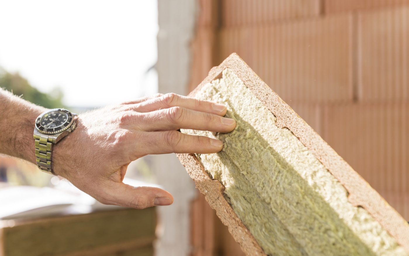 Hand touching mineral wool of internal insulation filled clay block