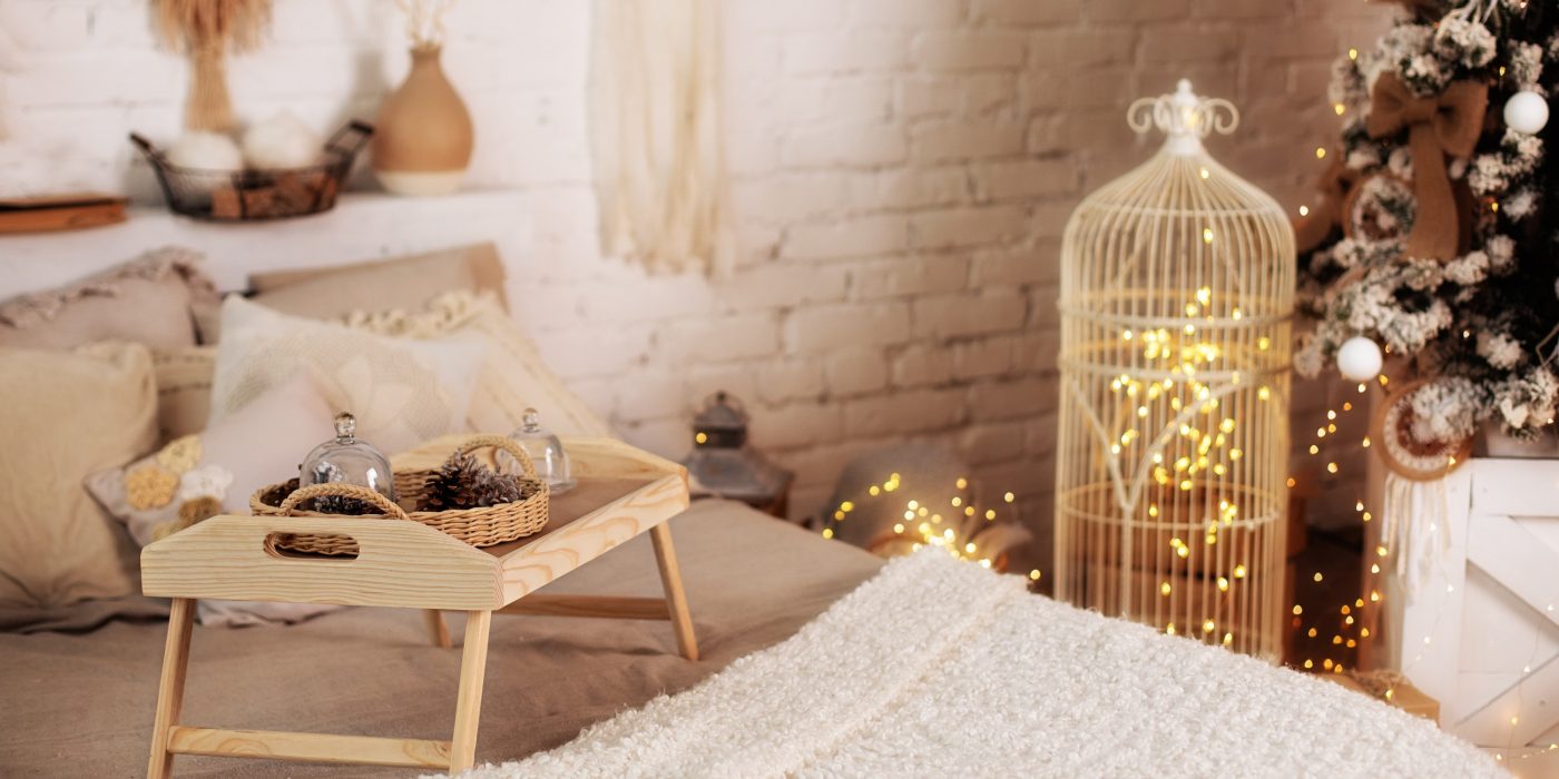 Wooden breakfast tray on bed in morning. Christmas room decor. Cozy New Year's composition. Cozy house interior on Xmas eve. Bedroom interior with small table on bed with cones, christmas decorations.