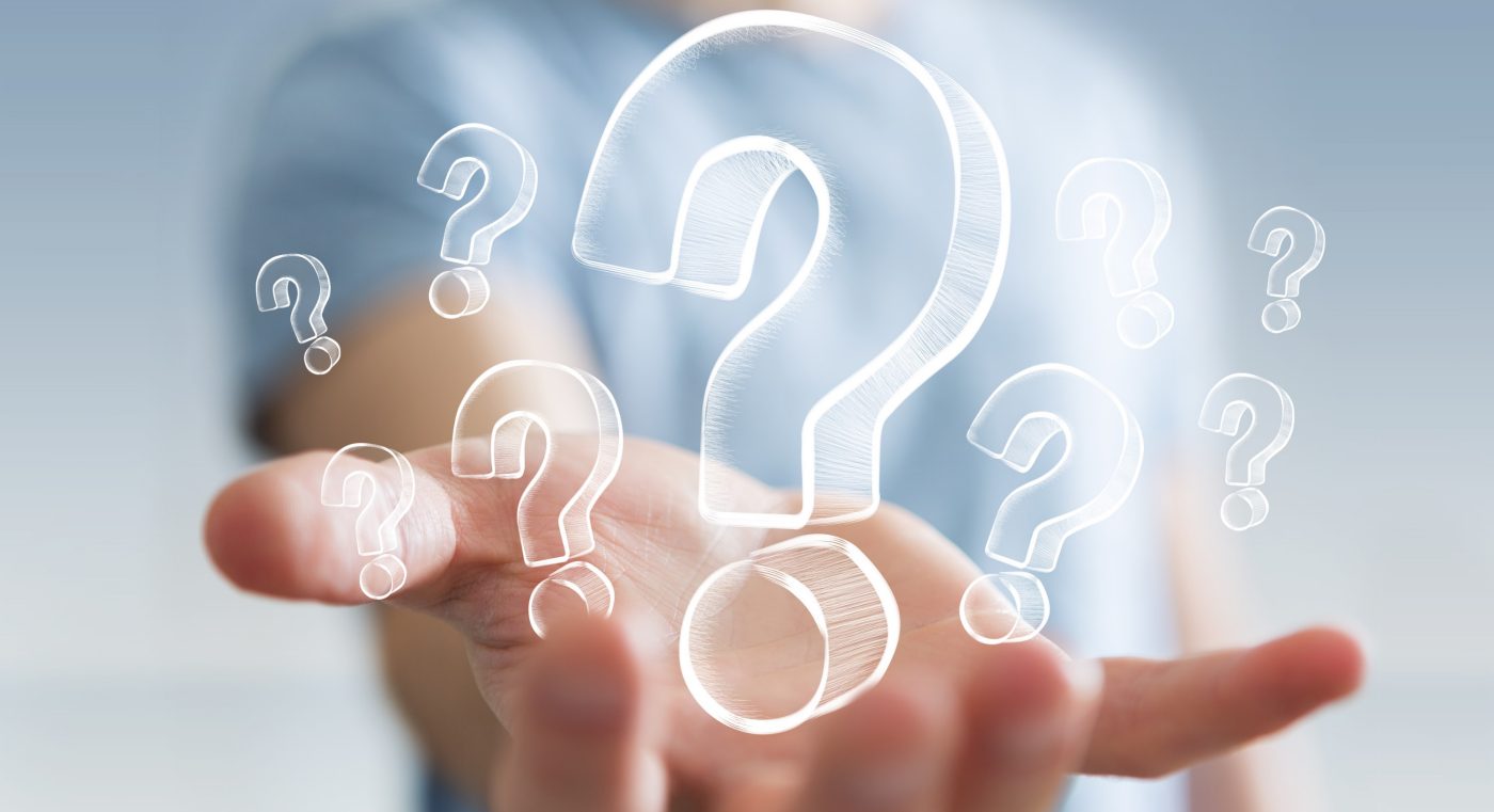 Businessman on blurred background holding hand drawn question marks