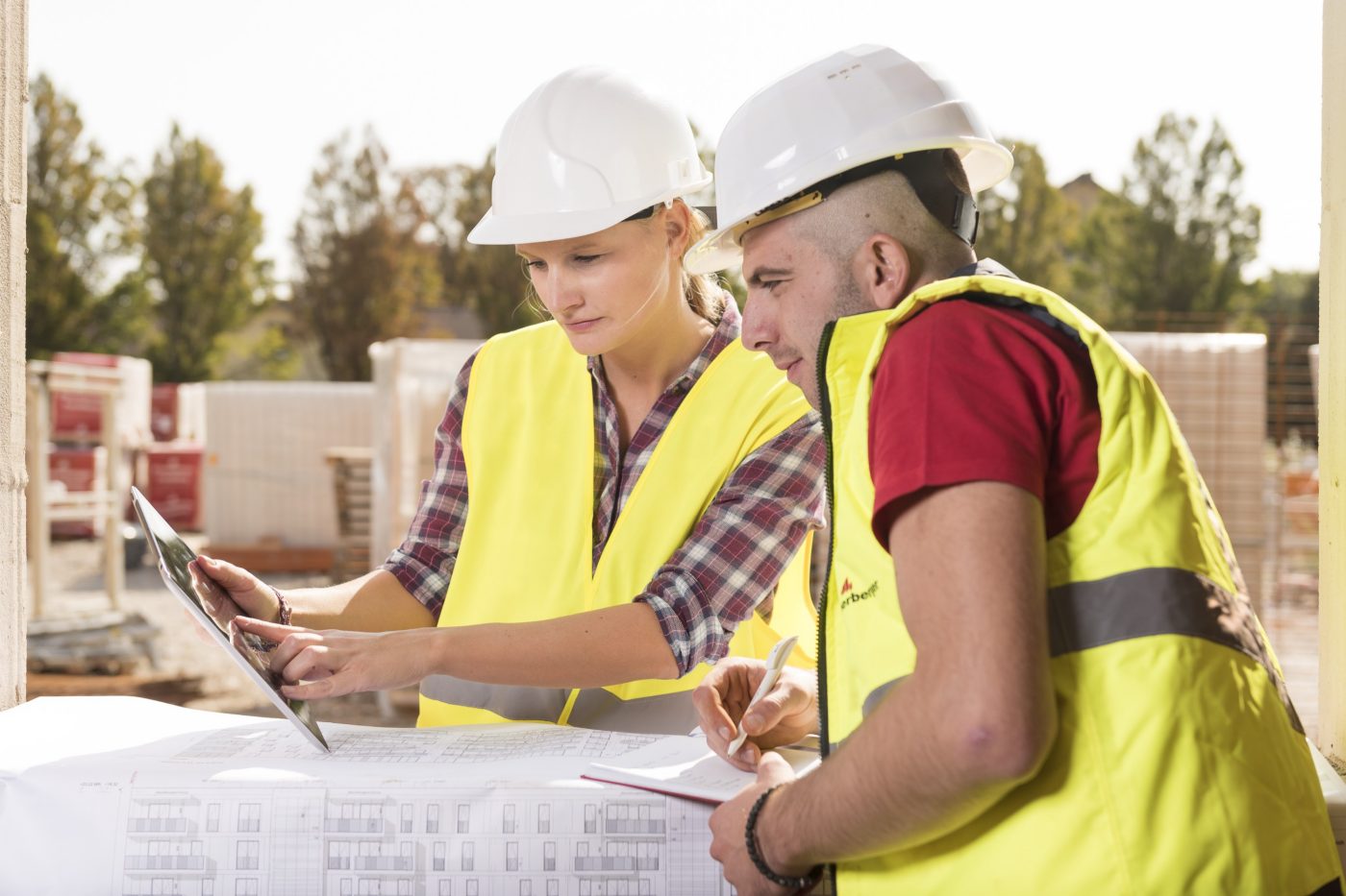 Woman pointing at tablet with male coworker taking notes at construction site, Fast Forward Commercial Excellence